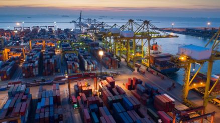 Container terminal at sunset with illuminated cranes and stacked containers, showcasing the efficiency of CHESSCON Yard View.
