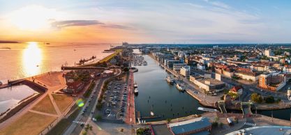 Panoramic view of Bremerhaven at sunset, featuring port facilities, waterways, and the city in the background.
