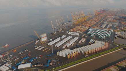Aerial view of Bremerhaven container port with cranes, containers, and large-scale stored goods such as wind turbine blades.