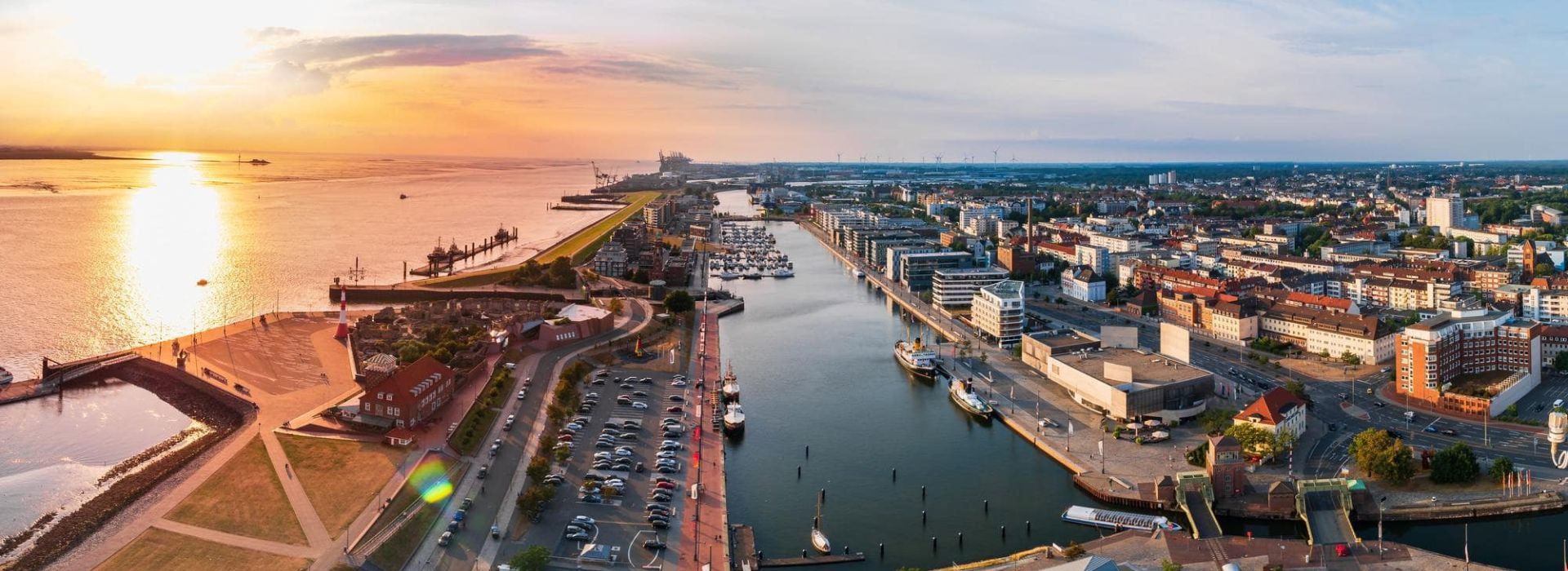 Panoramic view of Bremerhaven at sunset, featuring port facilities, waterways, and the city in the background.